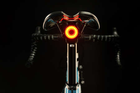 Close-up of illuminated bicycle tail light on black background