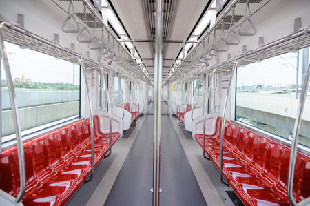 Empty elevated train coach with red seats. Inside of a train carriage