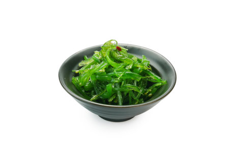 Traditional Japanese wakame seaweed salad with sesame seeds on black bowl isolated on backgroundの写真素材