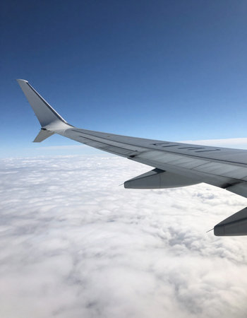 Wing of an airplane flying above the clouds in a sunny day.