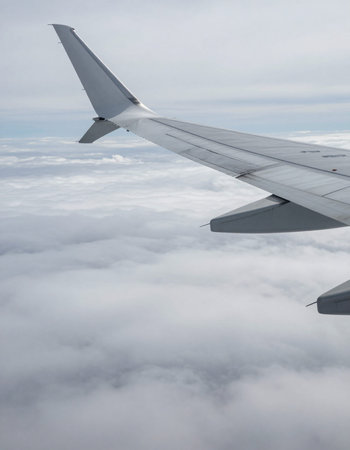 Wing of an airplane flying above the clouds, view from the window