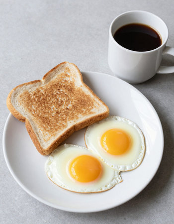 Breakfast with fried eggs, coffee and toast on a light background