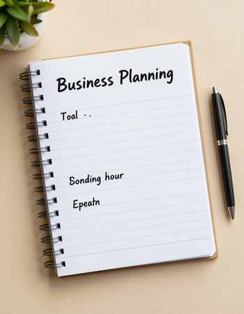 Business Planner text on notebook with pen on beige background.