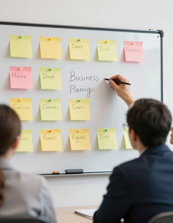 Businessman writing on sticky notes on whiteboard during business meeting in office