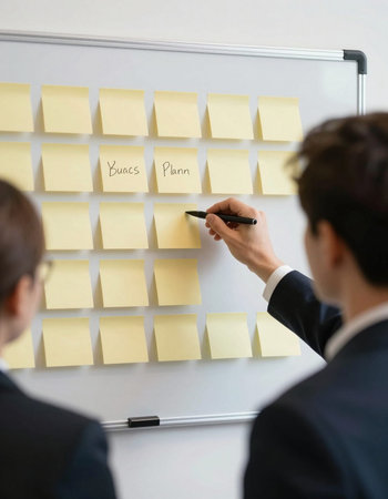 Businessman writing on sticky notes on whiteboard, focus on man