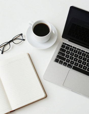 Desk table with laptop, coffee cup, notebook and glasses.