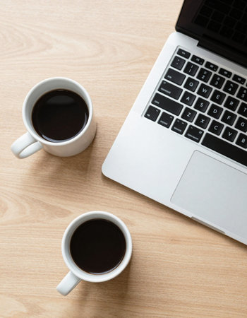 Laptop and two cups of coffee on wooden table, top view