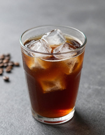 Glass of cola with ice cubes on grey table, closeup