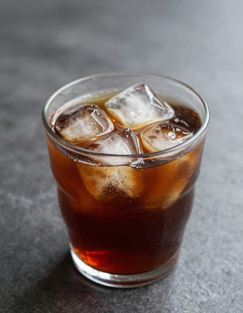 Cola with ice cubes in a glass on a dark background, vertical