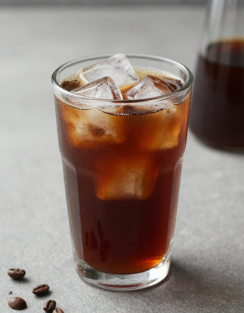 Cola with ice cubes and coffee beans on grey background, closeup