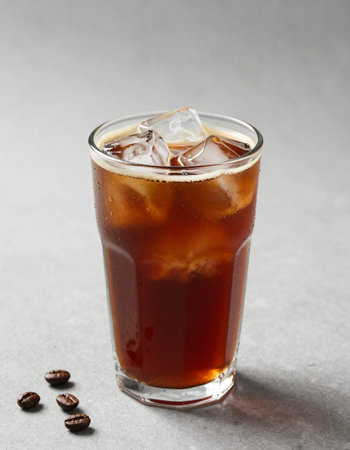 Coffee in a glass with ice on a gray background.