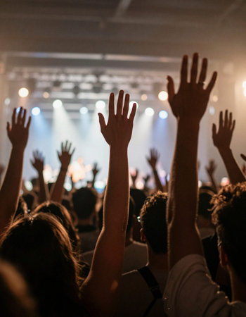 Crowd of people with hands raised in front of a concert stage