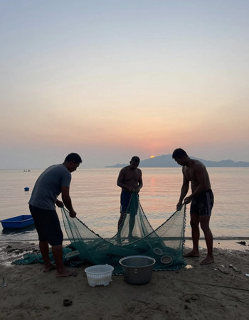 Fishermen casting net on the beach at sunset in Thailand.の写真素材