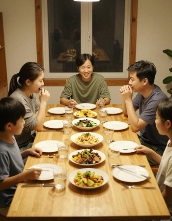 Family sitting at dining table, talking and having dinner together, smilingの写真素材
