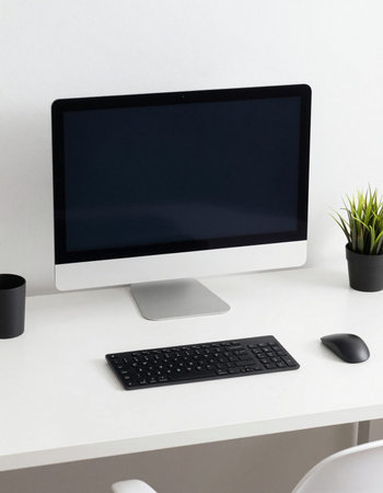 Modern workspace with computer, keyboard, mouse and plant on white table.