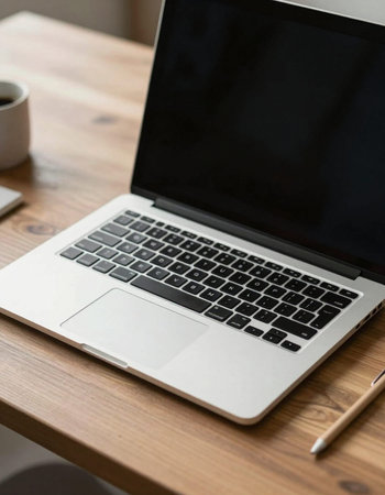 Laptop on a wooden table with a cup of coffee and a pencilの写真素材