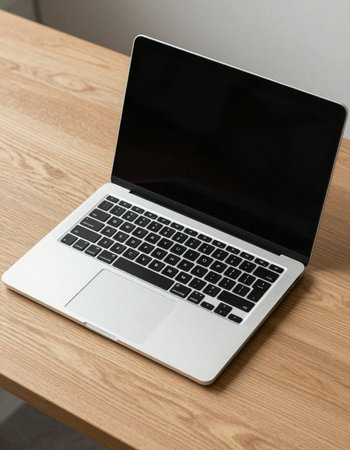 Laptop with blank screen on a wooden table in a modern office