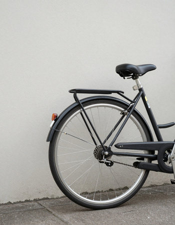 Black bicycle leaning against a gray wall with copy space for your text
