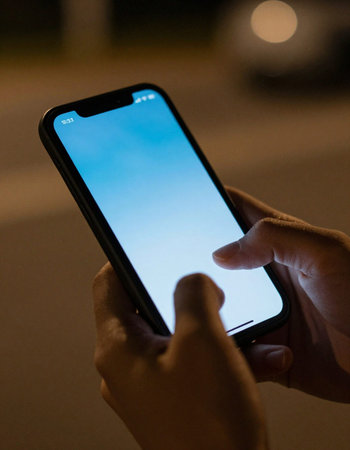 Close-up of man using mobile phone in the street at night