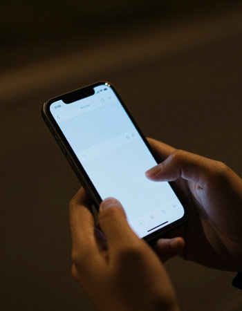 Woman using a smart phone in the dark, close-up shot
