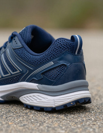A pair of blue running shoes on the ground. Shallow depth of field.