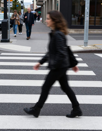 Blurred image of a woman crossing a pedestrian crossing in the city.