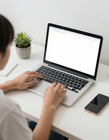 Cropped image of female hands typing on laptop with blank white screen