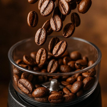 Coffee beans falling in a coffee grinder on a brown background