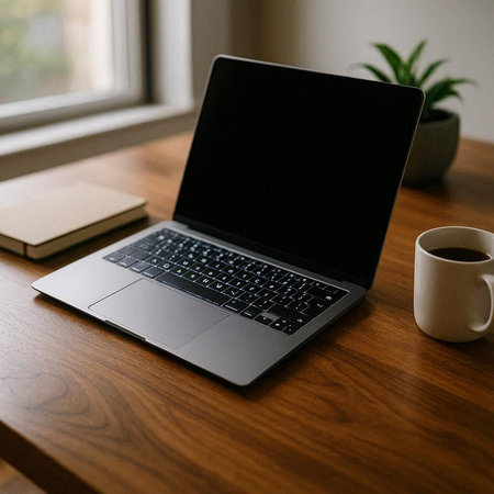 Laptop with blank screen and coffee cup on wooden table at home
