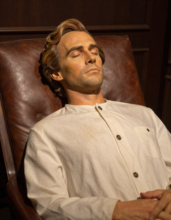 Handsome man with brown hair in a white shirt sitting in an armchair