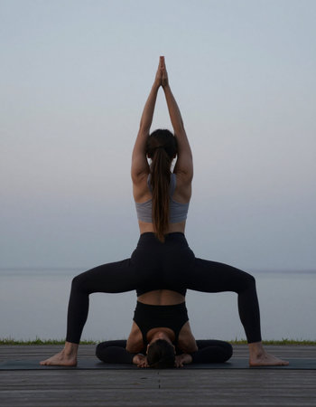 Young woman practicing yoga on a pier by the sea at sunset.