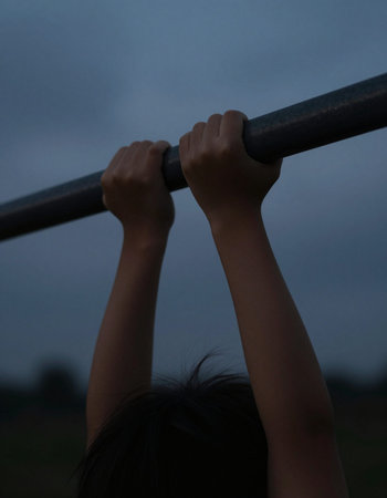 Close up shot of a girl doing pull-ups at the playground