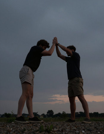 Friends giving high five in the countryside at sunset. Friendship concept.