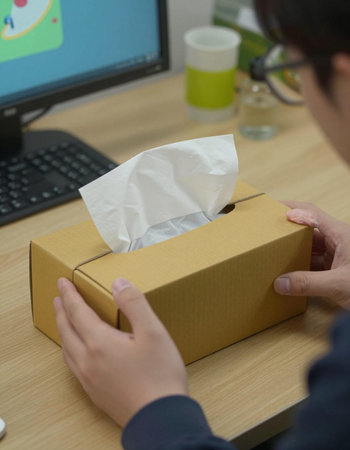 Young man with a box of tissues on the desk at home.