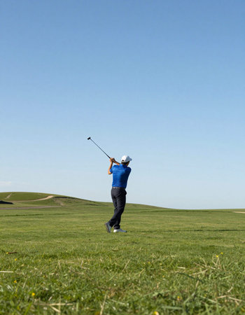 Golfer playing golf on a green with a blue sky in the background
