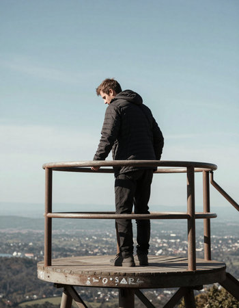 Young man standing on a viewing platform, looking at the city.