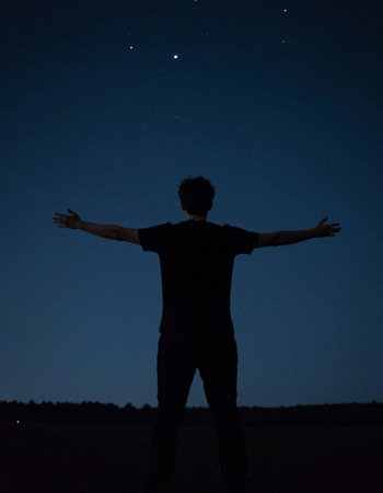 Silhouette of a man with arms outstretched against the night sky