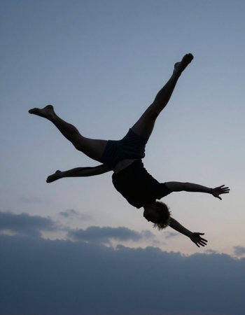 young man jumping in the air on a background of the evening skyの写真素材