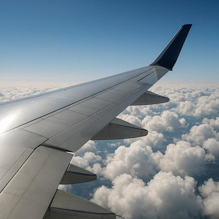 View of the wing of a passenger plane flying above the clouds.