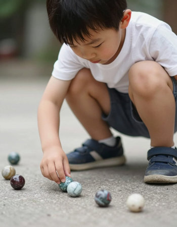 Asian boy playing marbles in the park