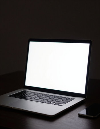 Laptop with blank screen on the table in the dark room.
