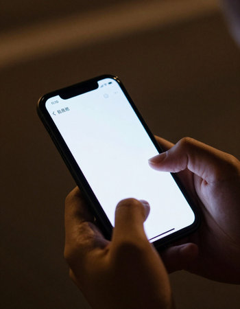 Close up of male hand holding a new Apple iPhone X smartphone with blank screen on display.