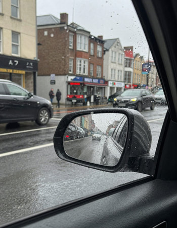 Rain drops on the rearview mirror of a car in the city