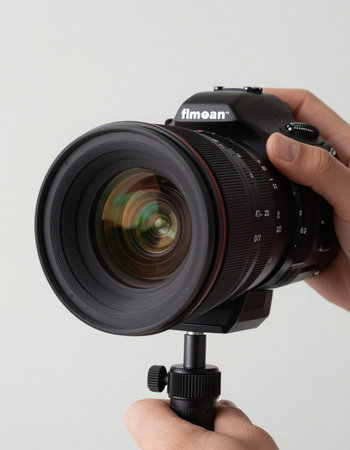 Man's hand holding DSLR camera, isolated on white background.