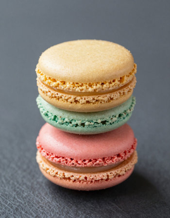 Colorful macaroons on black background. French sweet dessert.