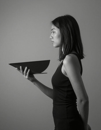 Studio shot of young beautiful Asian woman holding a bowl against gray backgroundの写真素材