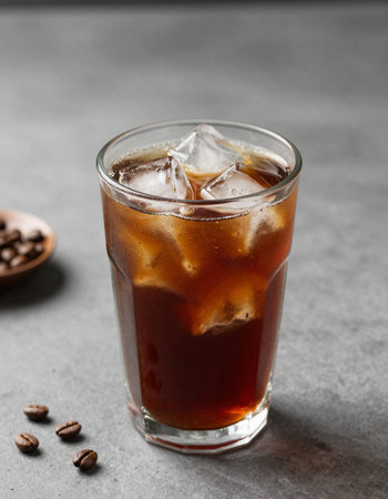 Glass of cola with ice cubes on grey table, closeup