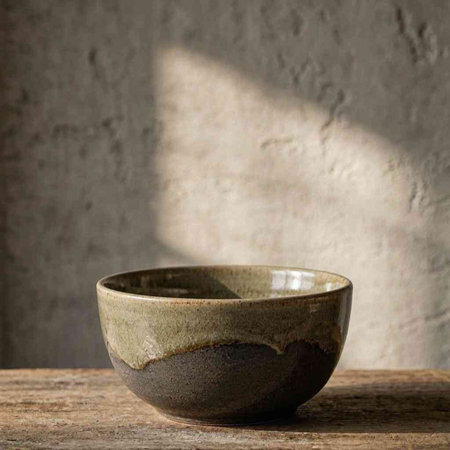 Empty ceramic bowl on wooden table with shadow on concrete wall background.