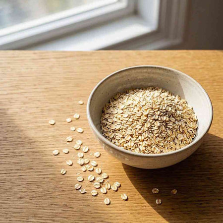 Oat flakes in a bowl on a wooden table, top view