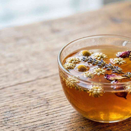 Herbal tea in a glass cup with dried lavender flowers on a wooden table